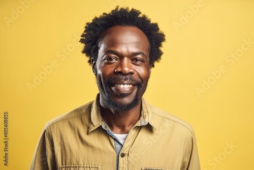 A man with a beard and a yellow shirt is smiling