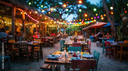 A wide-angle shot capturing a festive outdoor dining area at dusk  with colorful string lights illuminating the space and multiple tables set up for guests