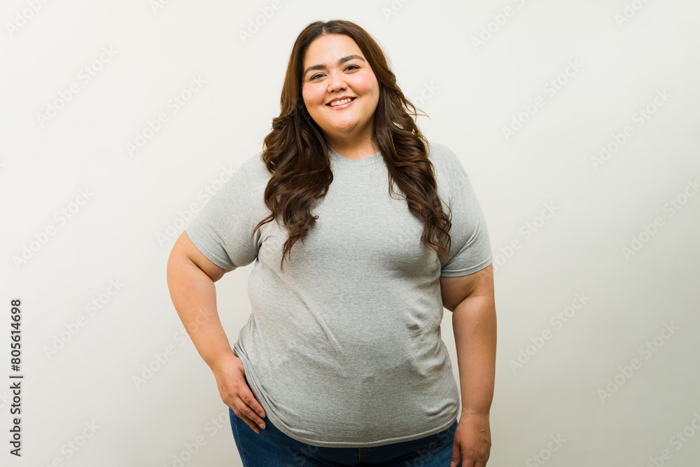 Happy overweight Latin woman standing confidently in a studio while wearing a gray t-shirt for a mockup product shot