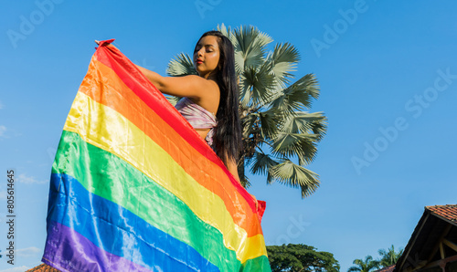 Retrato de una joven lesbiana sosteniendo una bandera del arco iris al aire libre photo