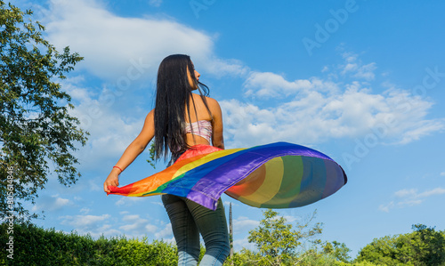 joven mujer hispanoamericana al aire libre con la bandera del orgullo gay  photo