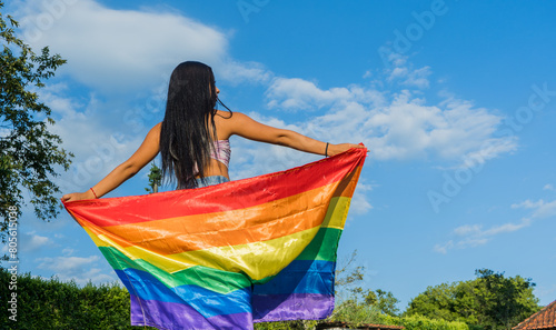 joven mujer de espaldas con la bandera del orgullo gay aal aire libre  photo