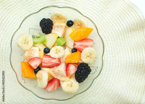 Imagen horizontal con un plato de ensalada de frutas saludables sobre un fondo claro