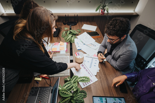 Two professionals discuss business strategies and review documents at a busy office workspace  demonstrating effective teamwork and collaboration.