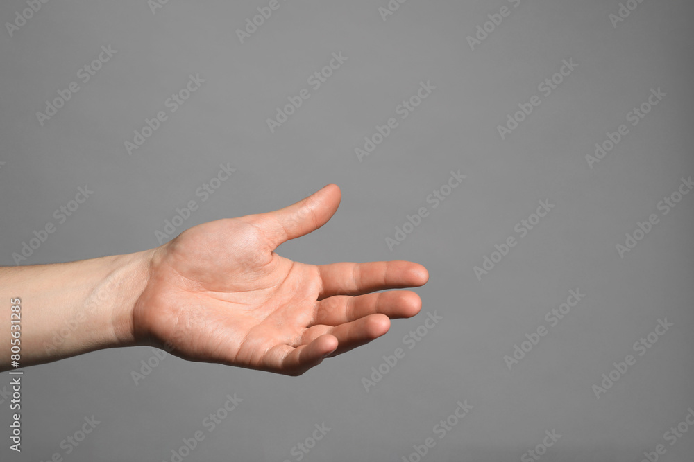 Man holding something in hand on grey background, closeup. Space for text Man holding something in hand on grey background, closeup. Space for text