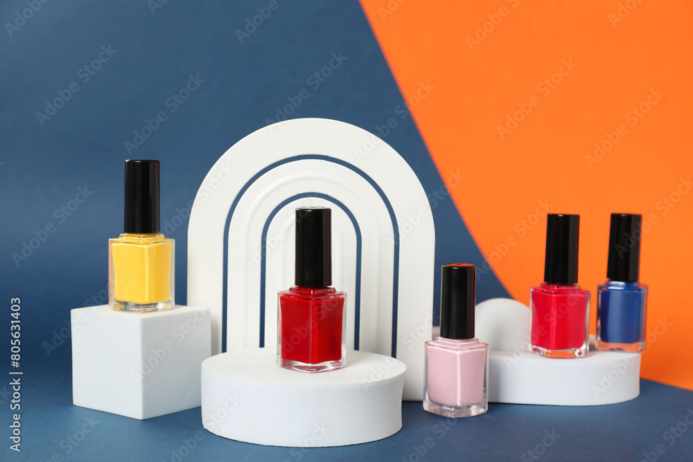 Stylish presentation of bright nail polishes in bottles on color background Stylish presentation of bright nail polishes in bottles on color background