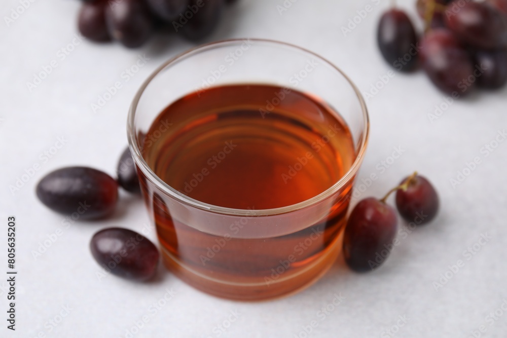 Wine vinegar in glass bowl and grapes on light grey table, closeup Wine vinegar in glass bowl and grapes on light grey table, closeup