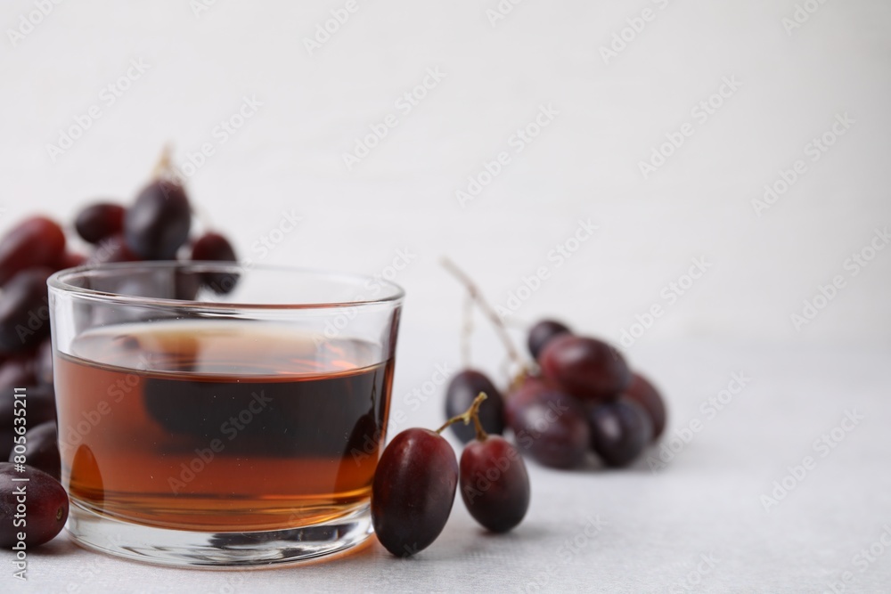 Wine vinegar in glass bowl and grapes on light grey table, space for text Wine vinegar in glass bowl and grapes on light grey table, space for text
