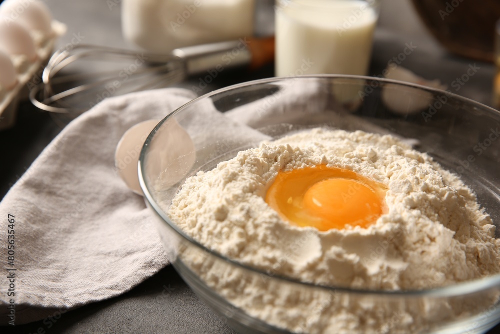 Making dough. Flour with egg yolk in bowl on grey table, closeup Making dough. Flour with egg yolk in bowl on grey table, closeup