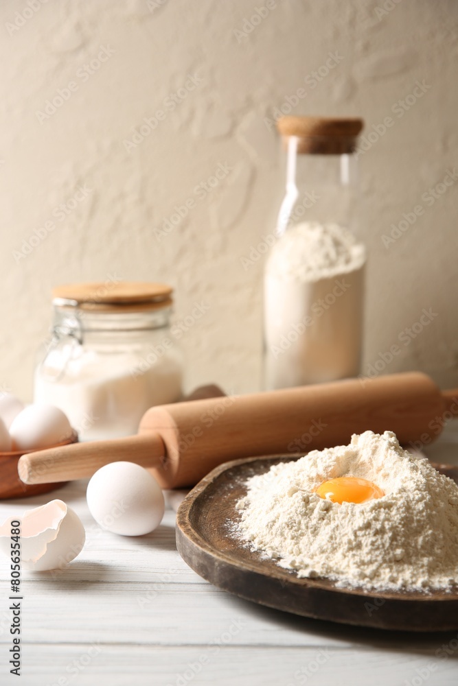 Making dough. Pile of flour with yolk, rolling pin and eggs on white wooden table, closeup Making dough. Pile of flour with yolk, rolling pin and eggs on white wooden table, closeup