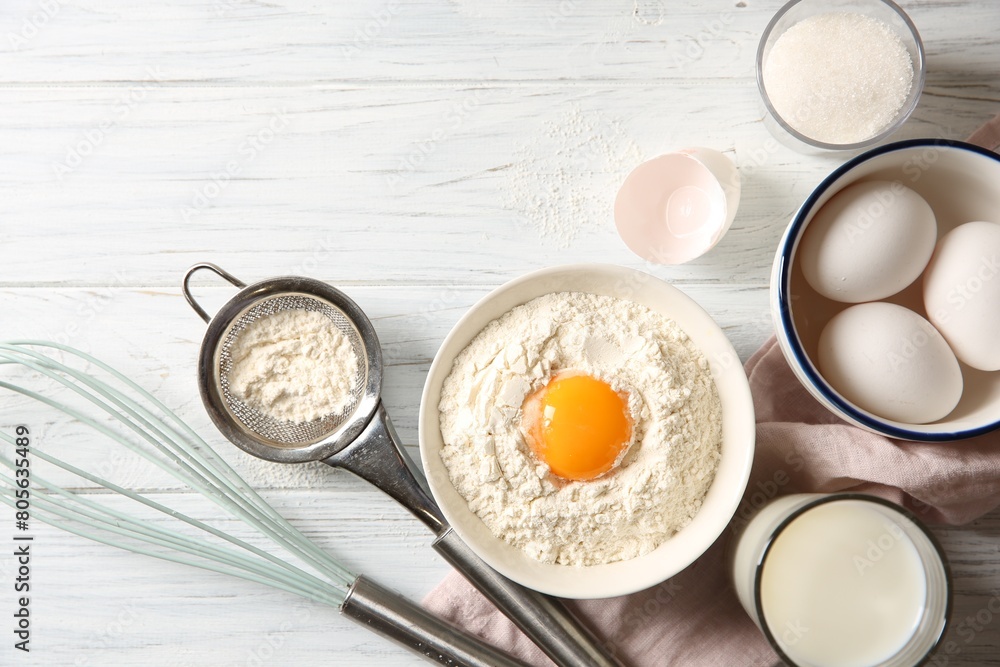 Flour with yolk in bowl and other ingredients for dough on white wooden table, flat lay Flour with yolk in bowl and other ingredients for dough on white wooden table, flat lay