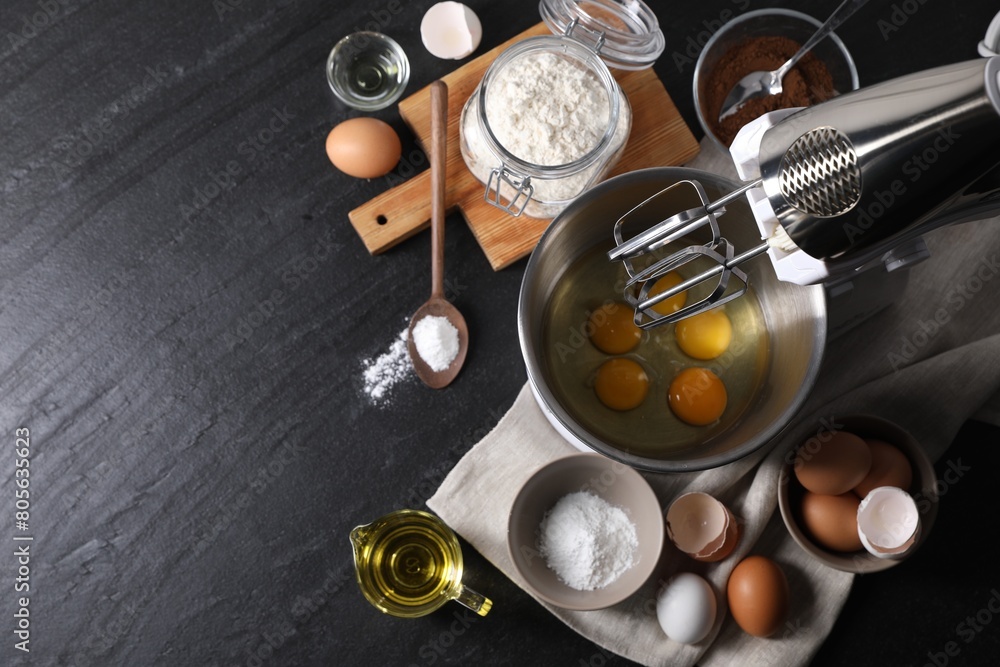 Making dough. Raw eggs in bowl of stand mixer and ingredients on black table, flat lay Making dough. Raw eggs in bowl of stand mixer and ingredients on black table, flat lay