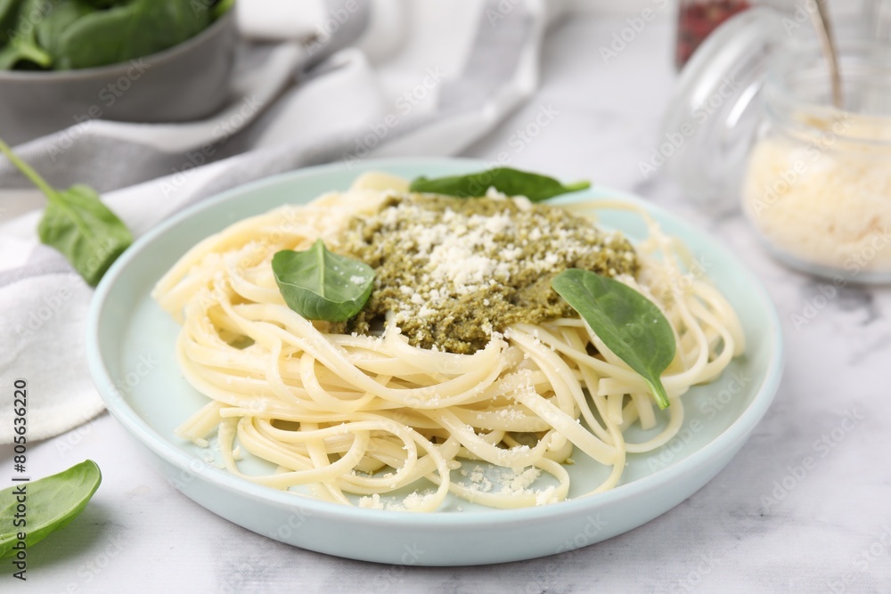 Tasty pasta with spinach, cheese and sauce on white marble table
