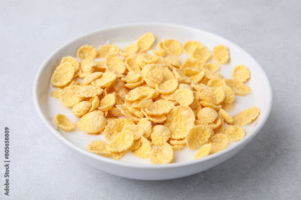 Breakfast cereal. Corn flakes and milk in bowl on light grey table, closeup Breakfast cereal. Corn flakes and milk in bowl on light grey table, closeup