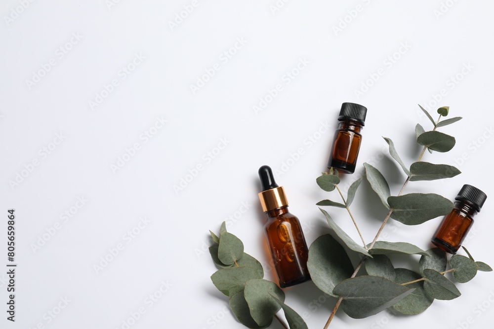 Aromatherapy. Bottles of essential oil and eucalyptus branches on white background, flat lay. Space for text Aromatherapy. Bottles of essential oil and eucalyptus branches on white background, flat lay. Space for text