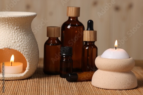 Different aromatherapy products and burning candles on table  closeup