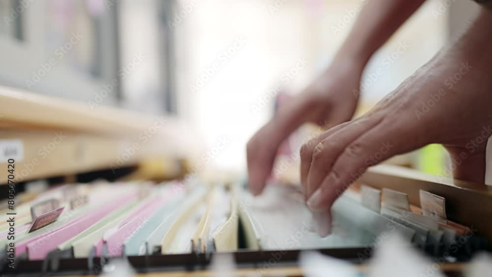 A person is reaching into a filing cabinet drawer. The drawer is full of papers and the person is trying to find something specific