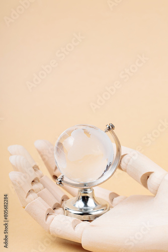 Glass Globe in Cyborg's Palm on Beige Background, Concept of Technological Protection from Environmental Disasters