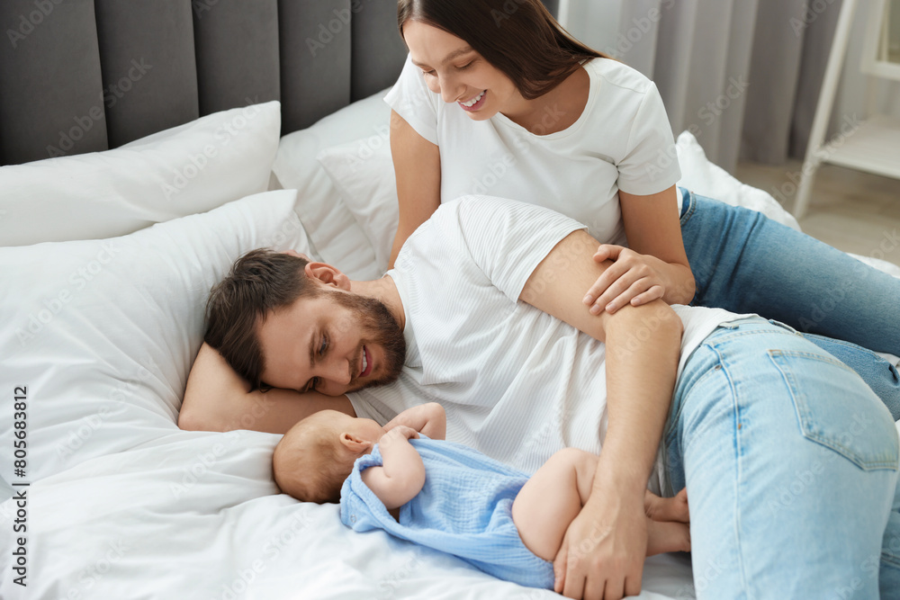 Happy family. Parents with their cute baby on bed indoors Happy family. Parents with their cute baby on bed indoors