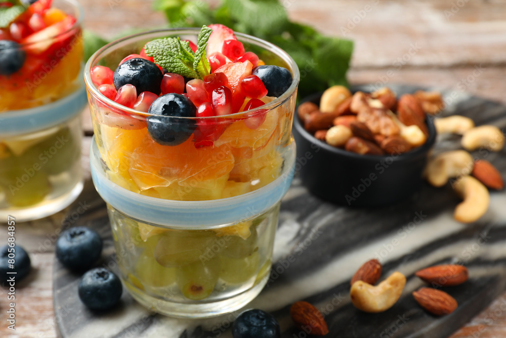 Delicious fruit salad, fresh berries, mint and nuts on wooden table Delicious fruit salad, fresh berries, mint and nuts on wooden table