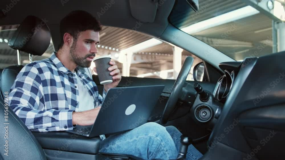 Man looking at laptop screen, drinking coffee in the car. Slow motion Man looking at laptop screen, drinking coffee in the car. Slow motion