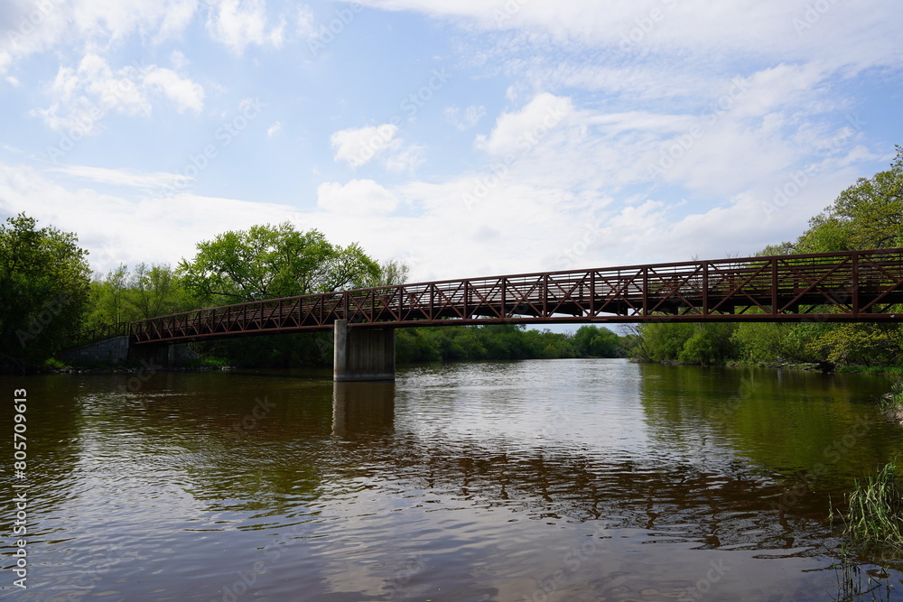 An iron steel walking path bridge stretches across a river. An iron steel walking path bridge stretches across a river.