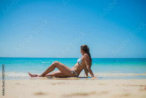 mujer hispanoamericana sentada en la playa a orillas del mar en vacaciones 