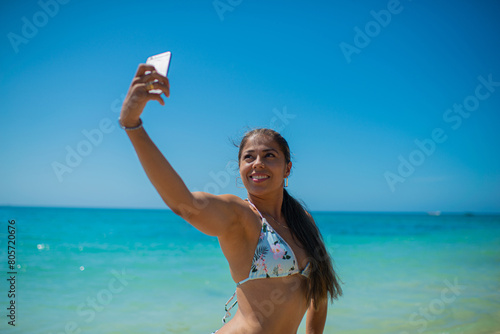 mujer joven hispanoamericana en la playa tomando una auto foto en vacaciones  photo