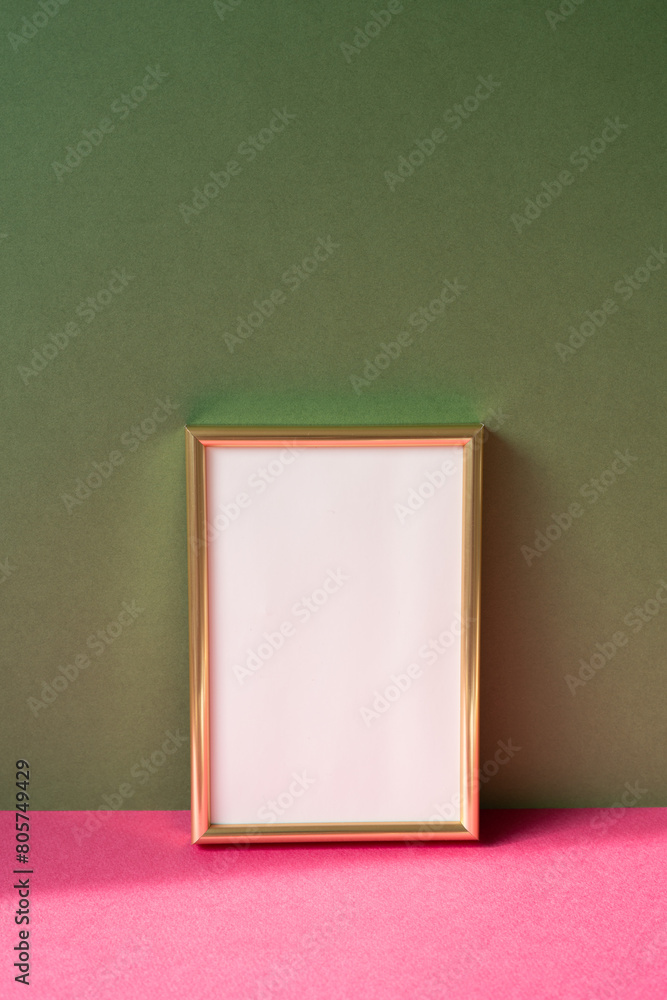 Gold picture frame with copy space on pink table. khaki green wall background