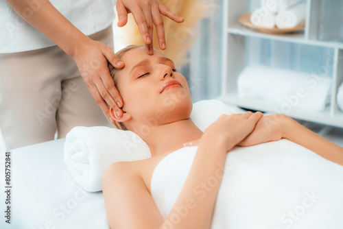 Caucasian woman enjoying relaxing anti-stress head massage and pampering facial beauty skin recreation leisure in dayspa modern light ambient at luxury resort or hotel spa salon. Quiescent photo