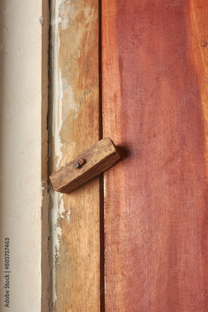 unprofessionally installed black tower bolt bolt hinge and lock on wooden door, non standard interior installation in close-up with copy space