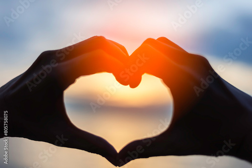 Couple doing heart shape with their hands on shore and love sign background