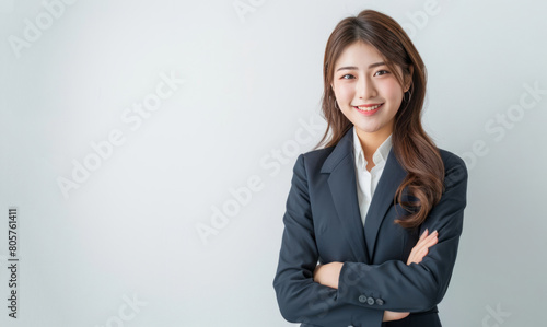 A female manager, dressed in a business suit with her arms crossed, smiles and looks at the camera against a white background. photo