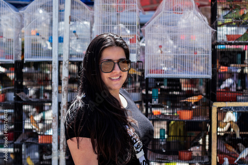 Mujer latina paseando por un mercado donde tienen jaulas de pájaros