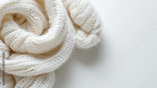 A white knitted scarf lies on a white table, near a pair of scissors