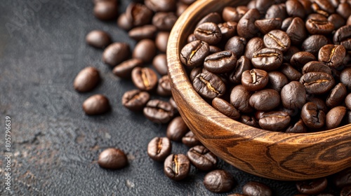  A wooden bowl holding coffee beans next to an adjacent stack on a black countertop