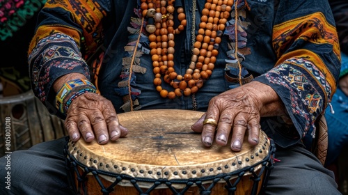  A tight shot of hands resting atop a drum adorned with beaded necklaces