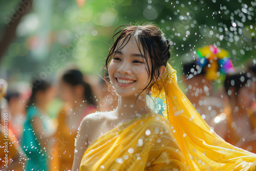 Young woman joyfully participating in a water festival, adorned in a bright yellow saree, surrounded by festive splashes
