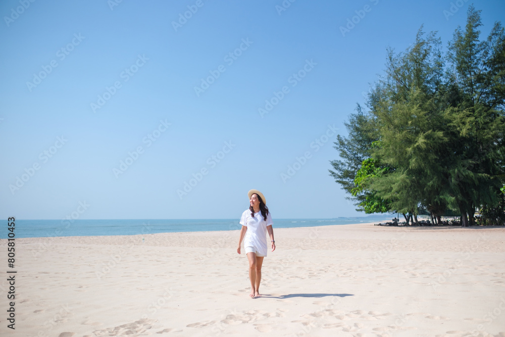 Portrait image of a young woman while strolling on the beach with the sea and blue sky background Portrait image of a young woman while strolling on the beach with the sea and blue sky background