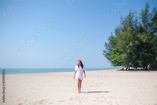Portrait image of a young woman while strolling on the beach with the sea and blue sky background © Farknot Architect