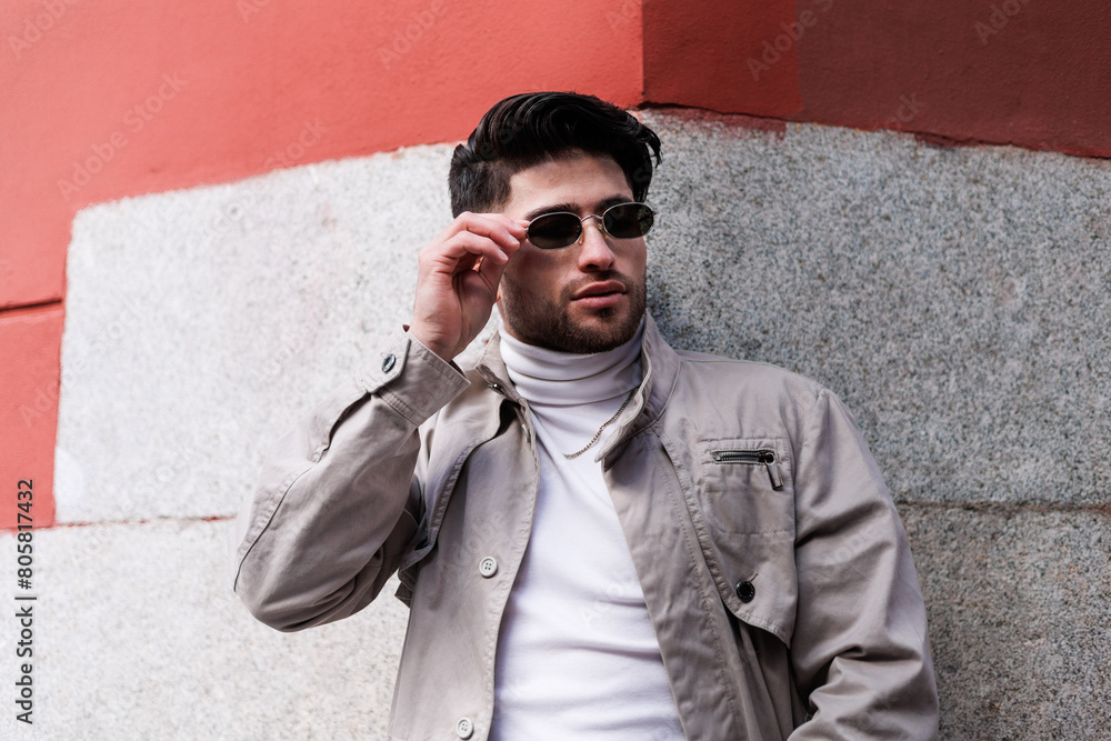 Handsome latin man with singlasses leaning on modern background.