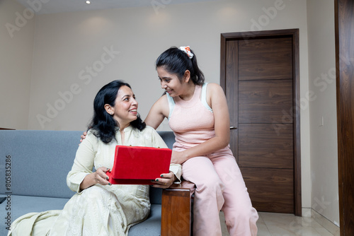 Indian teen daughter Giving Gift box to mother and congratulating her for mothers day