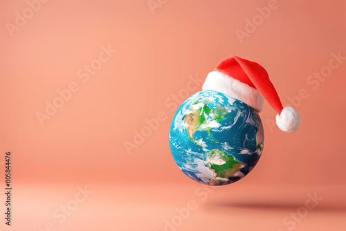 Earth globe with Santa hat floating against peach background.