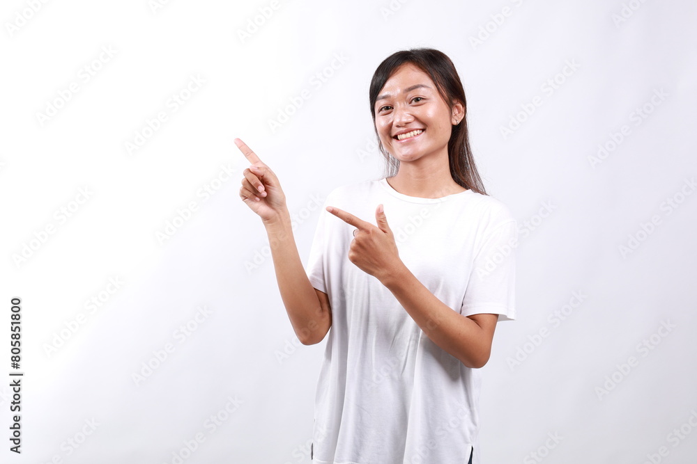Portrait of smiling asian young lady pointing fingers left, showing something aside on copy space, white background