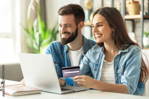 A happy young couple making a credit card payment on a laptop together at home.