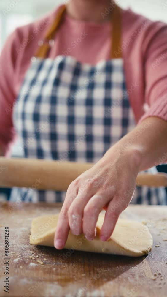 Close up vertical video of woman in kitchen rolling out dough with rolling pin on wooden board to make pasta - shot in slow motion Close up vertical video of woman in kitchen rolling out dough with rolling pin on wooden board to make pasta - shot in slow motion