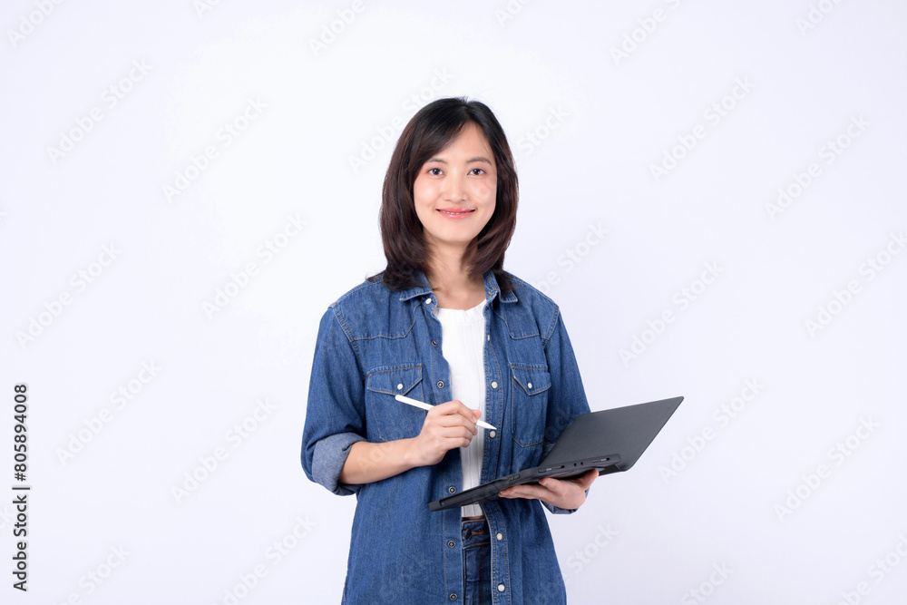Asian woman wearing denim jean is holding a tablet and a stylus against a white background. Asian woman wearing denim jean is holding a tablet and a stylus against a white background.