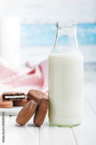 Chocolate Covered Cookies and Glass of Milk on white table.