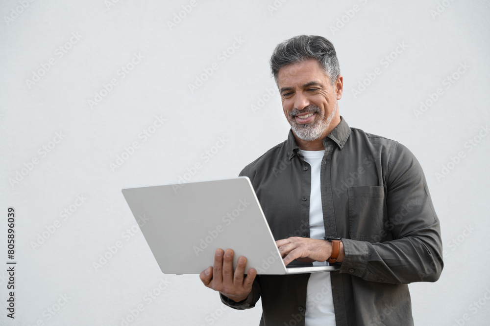 Mature 40s Indian happy man using wireless pc for business solutions, isolated on white background. Middle age freelance entrepreneur, latin hispanic businessman holding laptop computer, working busy Mature 40s Indian happy man using wireless pc for business solutions, isolated on white background. Middle age freelance entrepreneur, latin hispanic businessman holding laptop computer, working busy
