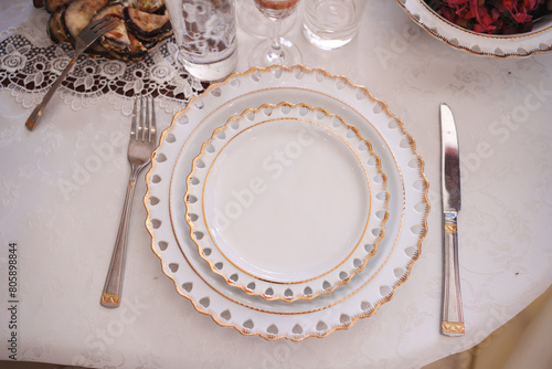 The table is served with classic white and gold dishes. Table setting for a banquet.